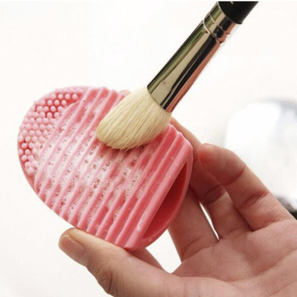 Silicone egg sponge scrubber in pink and purple for cleaning makeup brushes, by GlowCare.