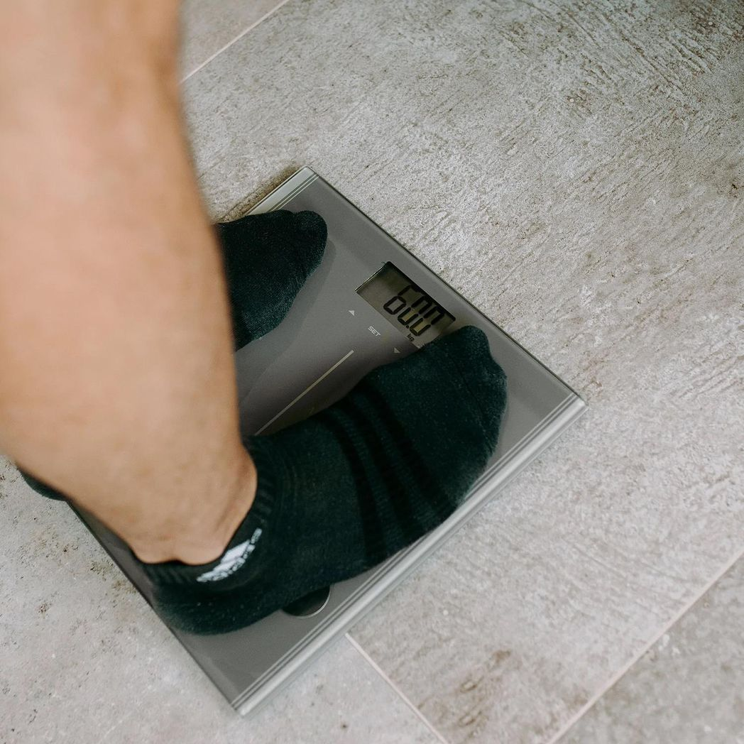 Silver Body Analysis Scale by Gymcline showing BMI report and daily calorie intake guide on its display.