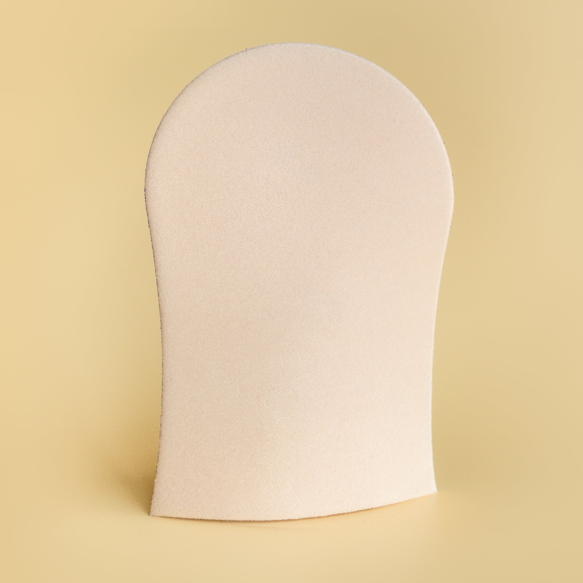 He-Shi GlowCare tanning mitt, machine washable, shown preventing stains while applying self-tanner on a hand.
